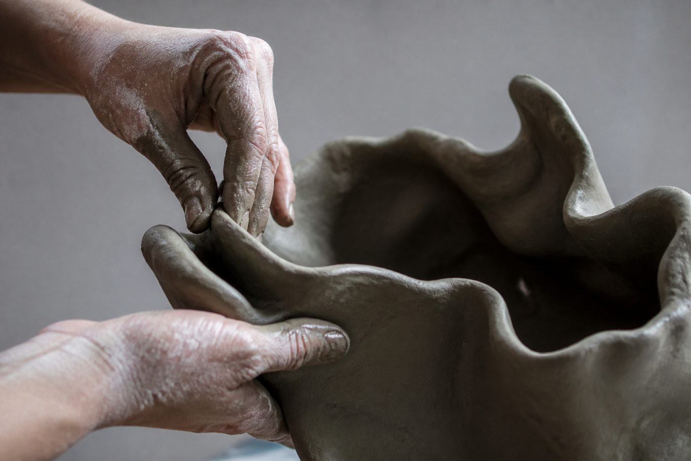 Hands pinching a sculptural clay form